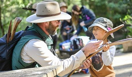 An Aboriginal guide shows boomerangs to a young child during a NSW National Parks' Aboriginal cultural tour. Photo: Adam Hollingworth/DCCEEW &copy; DPE