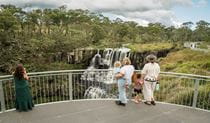Visitors enjoying impressive waterfall views from the cantilevered lookout at upper falls. Photo: David Waugh &copy;  DCCEEW
