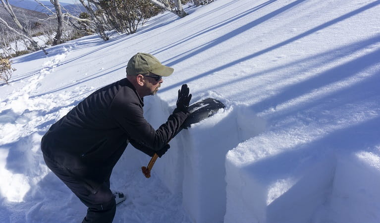 A man crouched over in snow, demonstrating avalanche survival skills. Photo: Avalanche Training Australia
