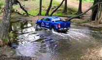 A blue 4WD vehicle makes a river crossing in bushland. Photo &copy; Getabout 4WD Adventures