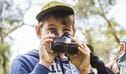 A child peeking over a pair of binoculars on a NPWS Discovery tour. Credit: Simone Cottrell/OEH &copy; Royal Botanic Gardens.