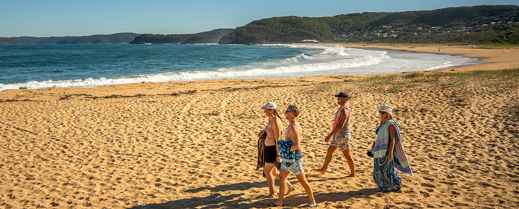 A group of people walking along Putty Beach in Bouddi National Park. Photo: John Spencer/DPIE