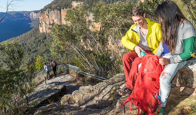 Walkers with a day pack sitting on Breakfast Rock along Govetts Leap descent. Photo: Simone Cottrell &copy; DPE