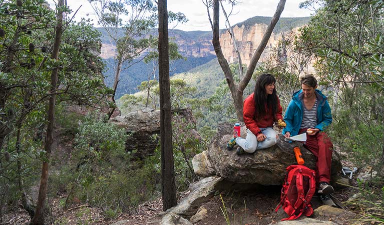 A couple sit on a rock near start of Grand Canyon track, Blue Mountains National Park. Photo: Simone Cottrell &copy; DPE