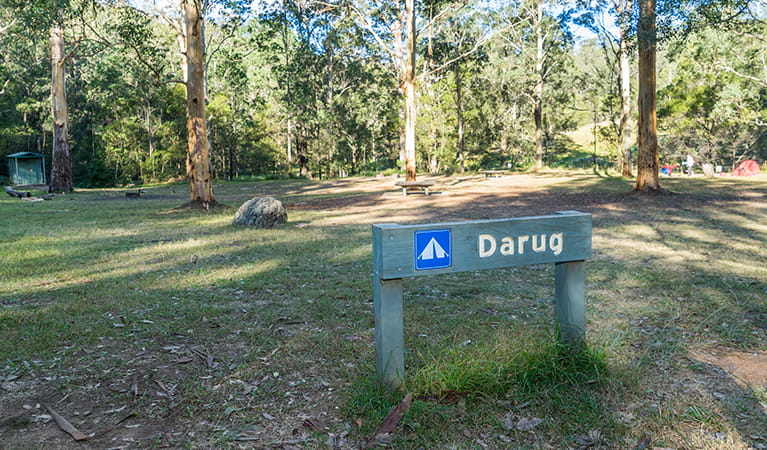 Signpost showing the Darug section of Euroka campground with toilets in the background. Photo: OEH/Simone Cottrell