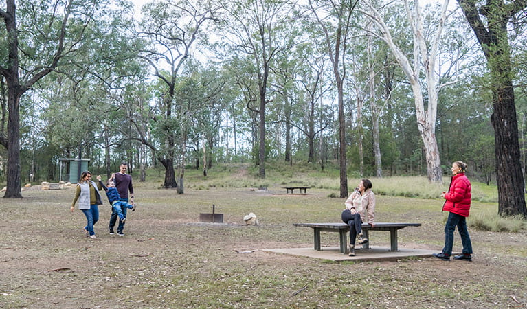 Family enjoy a walk around the Bennett Ridge section of Euroka campground with toilets in the background. Photo: OEH/Simone Cottrell