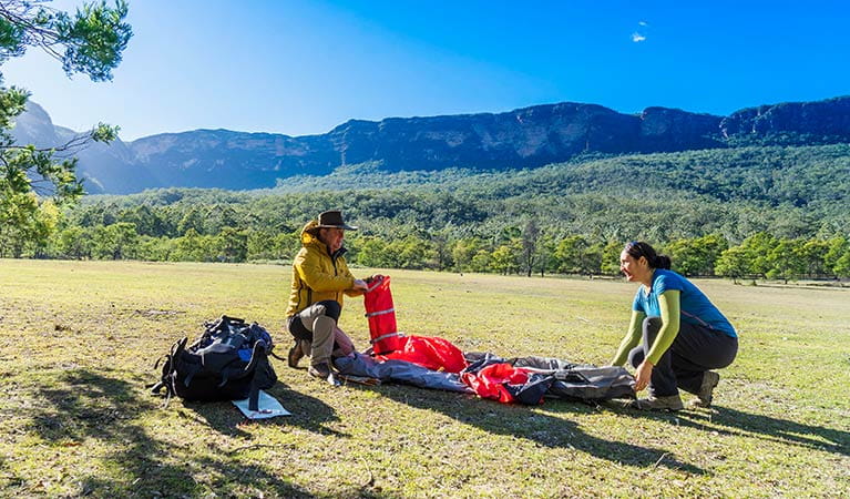 A couple set up a tent at Kedumba River Crossing campground, Blue Mountains National Park. Photo: Simone Cottrell/OEH