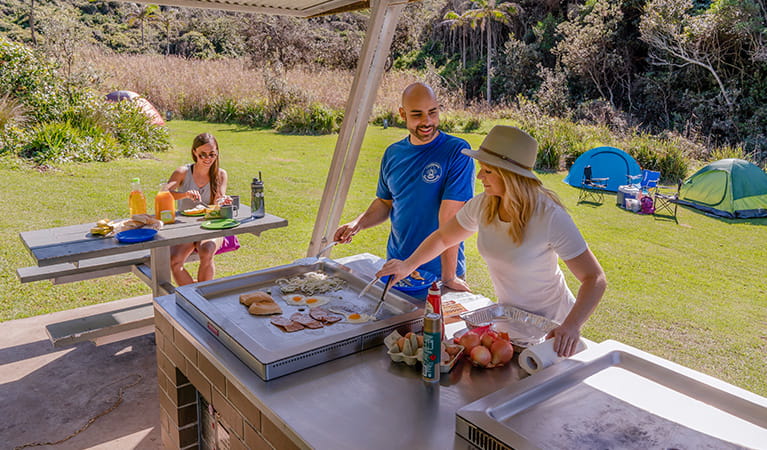 Campers under the barbecue shelter cooking and enjoying breakfast, Bouddi National Park. Photo: John Spencer/DPIE.