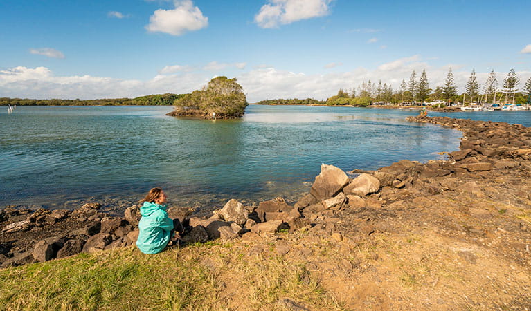 A woman sitting by the water at Brunswick River picnic area in Brunswick Heads Nature Reserve. Photo: John Spencer/DPIE