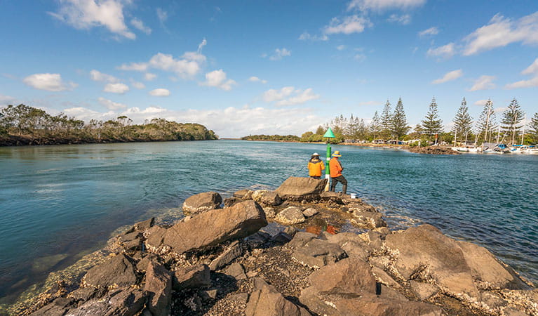 2 people fishing on the rocks at Brunswick River picnic area in Brunswick Heads Nature Reserve. Photo: John Spencer/DPIE