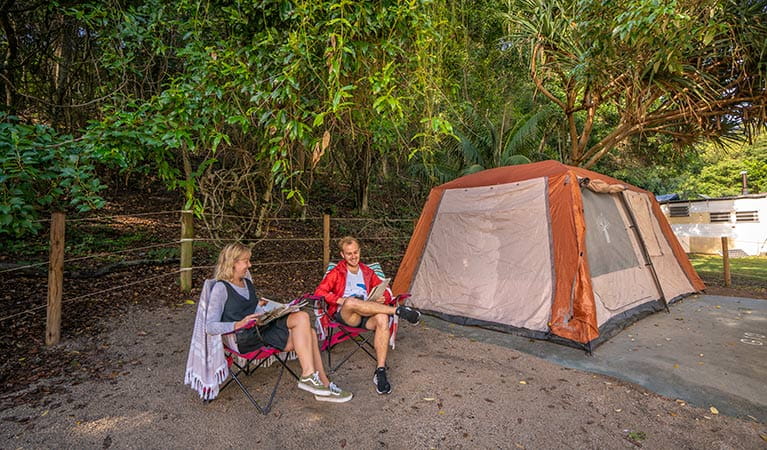 A couple relax, reading magazines beside their tent at Woody Head campground, Bundjalung National Park. Photo: John Spencer/OEH