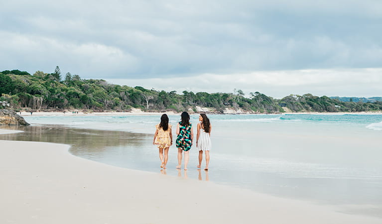 3 friends walking on The Pass beach in Cape Byron State Conservation Area. Photo: Sera Wright/DPIE