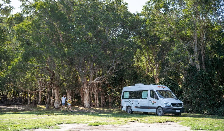 A couple walking across Kylies Beach campground to their campervan, Crowdy Bay National Park. Photo: Rob Mulally/DPIE