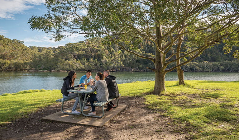 A group of friends at a picnic table next to Middle Harbour Creek in Davidson picnic area, Garigal National Park. Photo: John Spencer/DPIE
