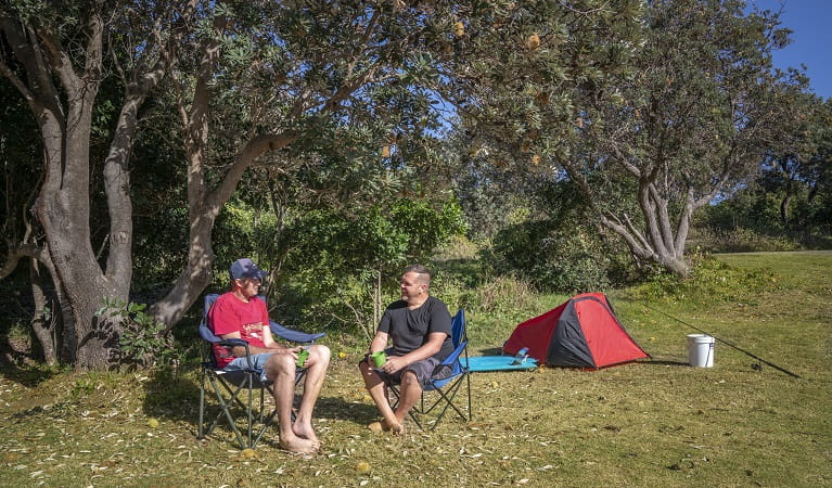 2 campers sitting down beside their tent talking at Racecourse campground. Photo: John Spencer/OEH