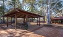View of covered picnic shelter with picnic table and barbecue against a backdrop of trees and rustic shed.  Photo: John Spencer/DPIE