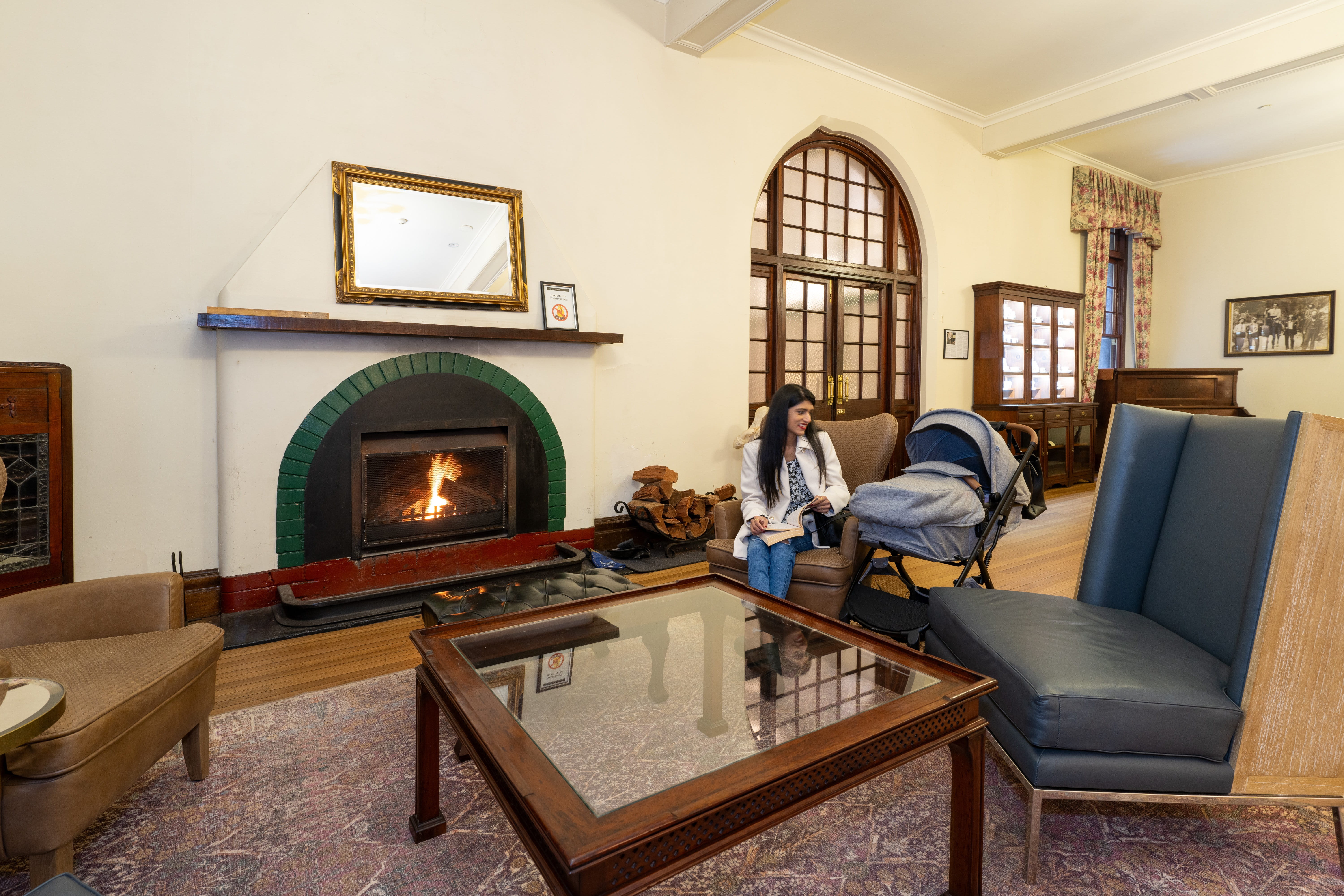 A woman relaxes with her baby, by the fireside in a lounge area at Jenolan Cave House, Jenolan Karst Conservation Reserve. Photo: Jenolan Caves &copy; DPE 