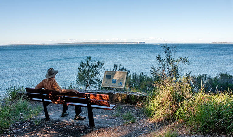 A man sits on a seat on a walking track in Jervis Bay National Park. Photo: Michael Van Ewijk &copy; OEH