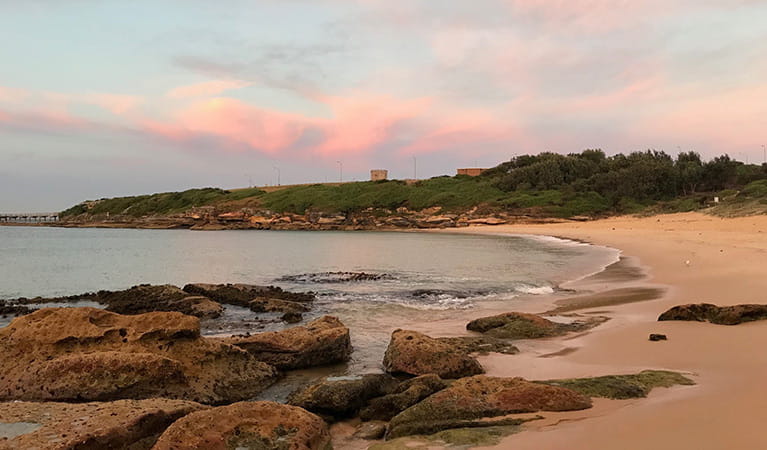 Congwong Beach at sunrise, with bushland and historic tower in the background. Photo: Stacy Wilson/OEH.