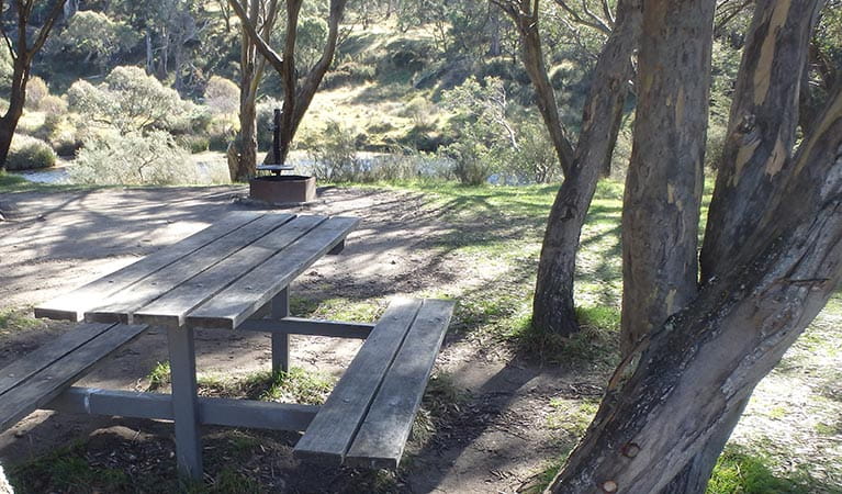 A timber picnic table at Gungarlin River, with a view of the river, Kosciuszko National Park. Photo: Andrew Miller/OEH