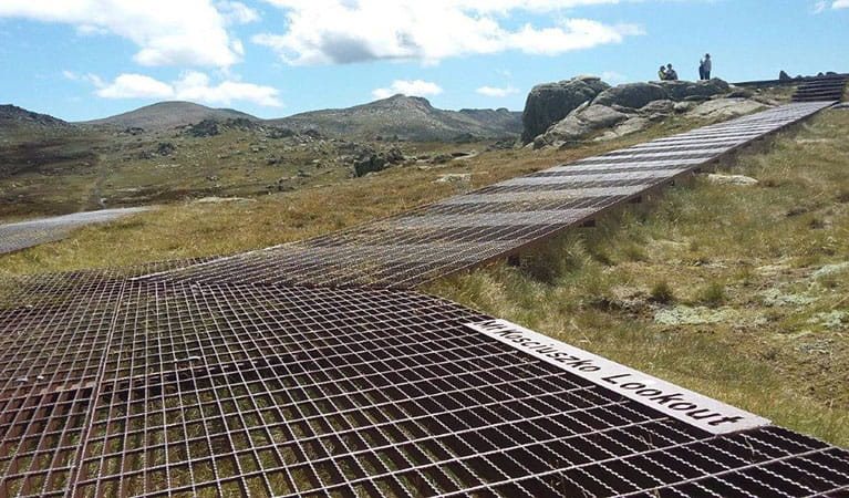 A metal mesh path heading up towards Kosciuszko lookout with mountains in the background in Kosciuszko National Park. Photo: Luke McLachlan &copy; DPIE