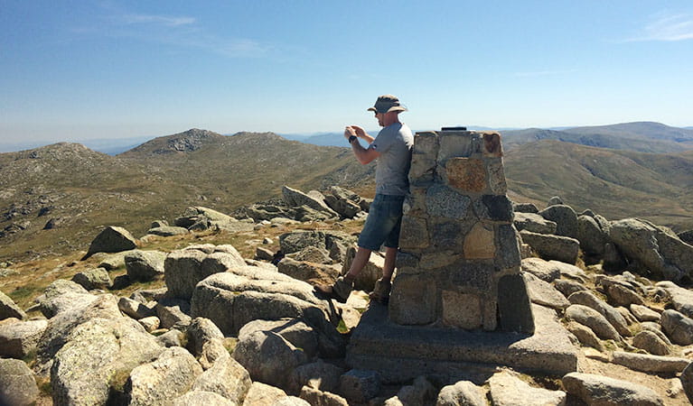 A hiker takes a photo from the summit of Mount Kosciuszko. Photo: Elinor Sheargold &copy; OEH