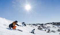 A skier and snowboarder speed down snowfields at Perisher Resort in Kosciuszko National Park. Photo: Images supplied courtesy of Perisher Ski Resort