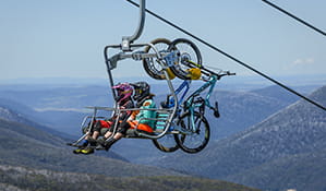 Two mountain bike riders with bikes take a chairlift to the top of Thredbo Mountain Bike Park, Kosciuszko National Park. Photo: Thredbo Resort