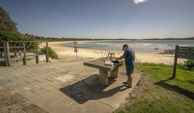 A fisherman cleaning his fish on a bench nearby the beach at Point Plomer campground, Limeburners Creek National Park. Photo: John Spencer/OEH