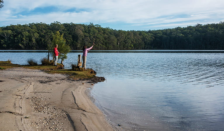 A man and a woman fishing on the shores of Burrill Lake in Meroo National Park. Photo: Michael Van Ewijk/DPIE