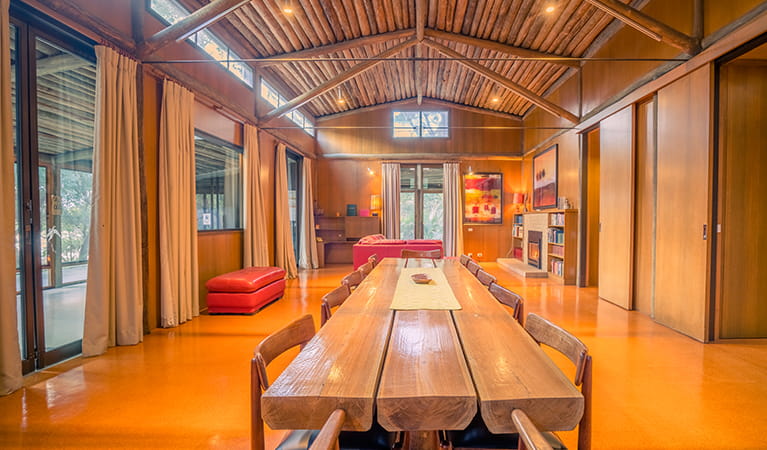 Long wooden dining table and red leather couches in Myher House. Photo: OEH/John Spencer