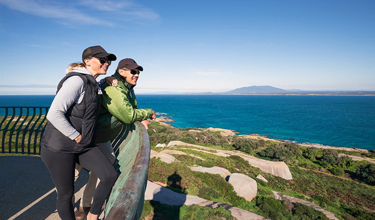 A woman and man lean on the balcony atop Montague Island Lighthouse. Photo: Daniel Tran/OEH