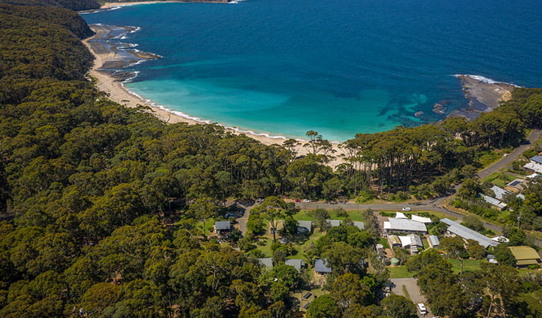 Aerial shot of Depot Beach cabins and campground, surrounded by bushland and showing proximity to the beach in Murramarang National Park. Photo: John Spencer &copy; DPIE