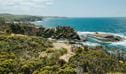Aerial view of 2 bushwalkers standing on North Head lookout taking in the coastal scene, Murramarang National Park. Credit: Remy Brand &copy; Remy Brand