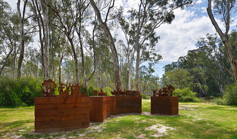 Wide view of sculpture set on grassy flat amongst river red gums in Murray Valley Regional Park. Photo: Gavin Hansford/DPIE