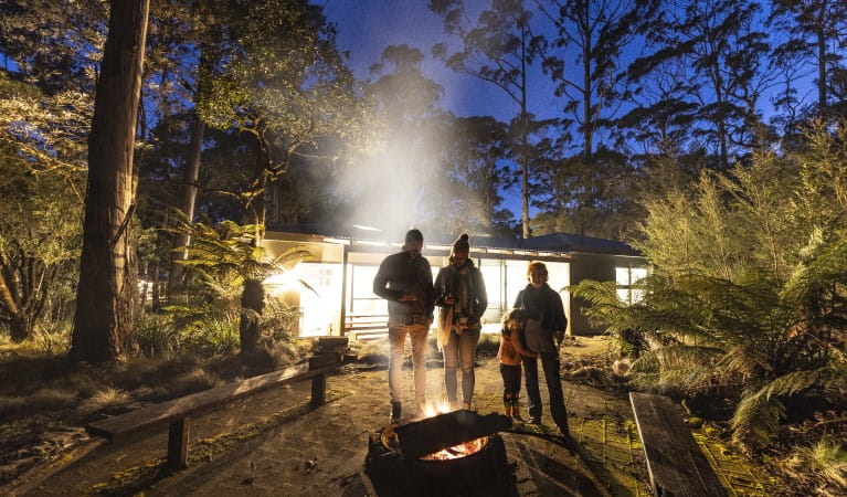 A family gathered around the firepit at night at The Residence, New England National Park. Photo: Mitchell Franzi &copy; DPIE