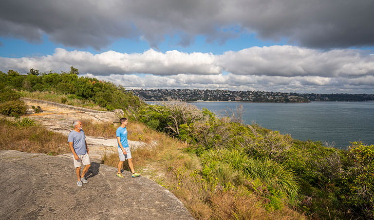 Two people walking along the rocks at Middle Head – Gubbuh Gubbuh in Sydney Harbour National Park. Photo: John Spencer/DPIE