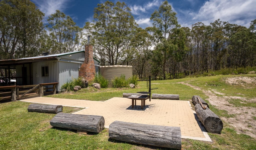 The outdoor wood barbecue surrounded by log benches at Four Bull Hut in Washpool National Park. Photo &copy; DPE