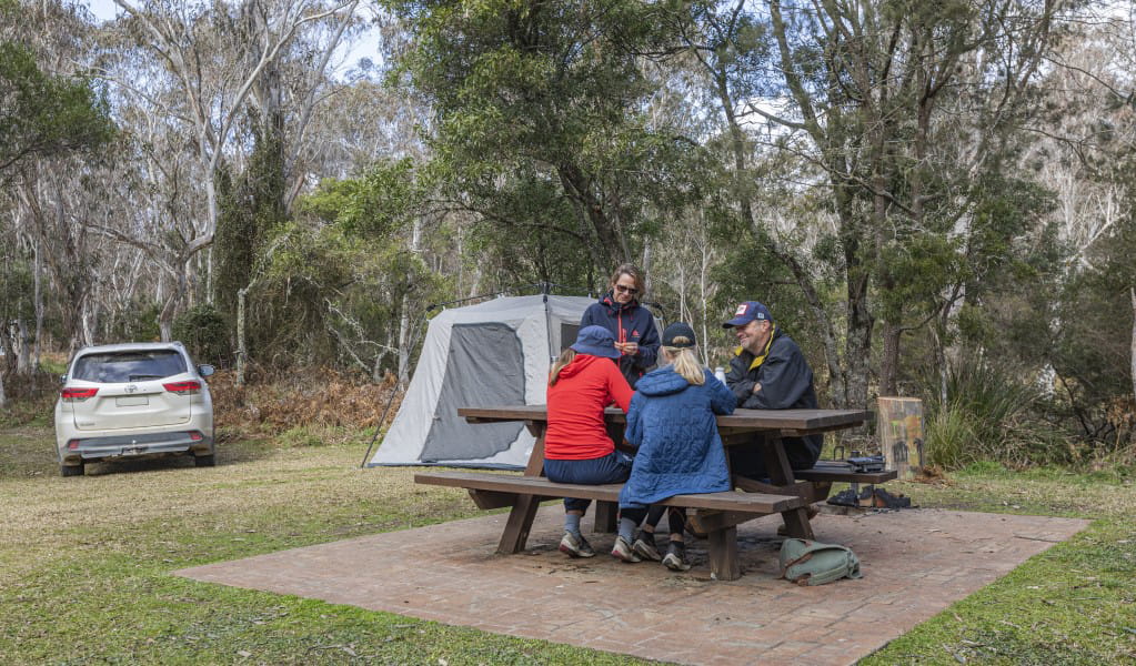A group of friends at a picnic table next to their tent at Mooraback campground in Werrikimbe National Park. Photo: Josh Smith &copy; DPE
