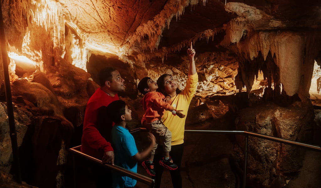 A woman points out a cave detail to her family during a guided tour of Mulwaree Cave, part of Wombeyan Caves. Credit: Remy Brand/DPE &copy; Remy Brand