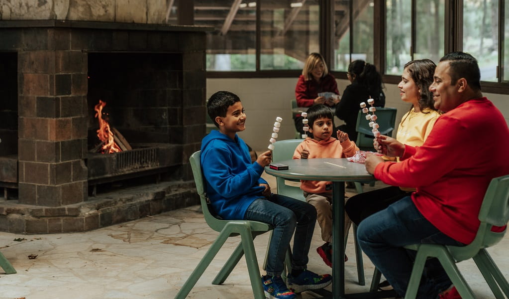 A family having fun preparing marshmallows to roast over an open fire at the Barmah communal dining room, Wombeyan Caves campground. Credit: Remy Brand/DPE &copy; Remy Brand