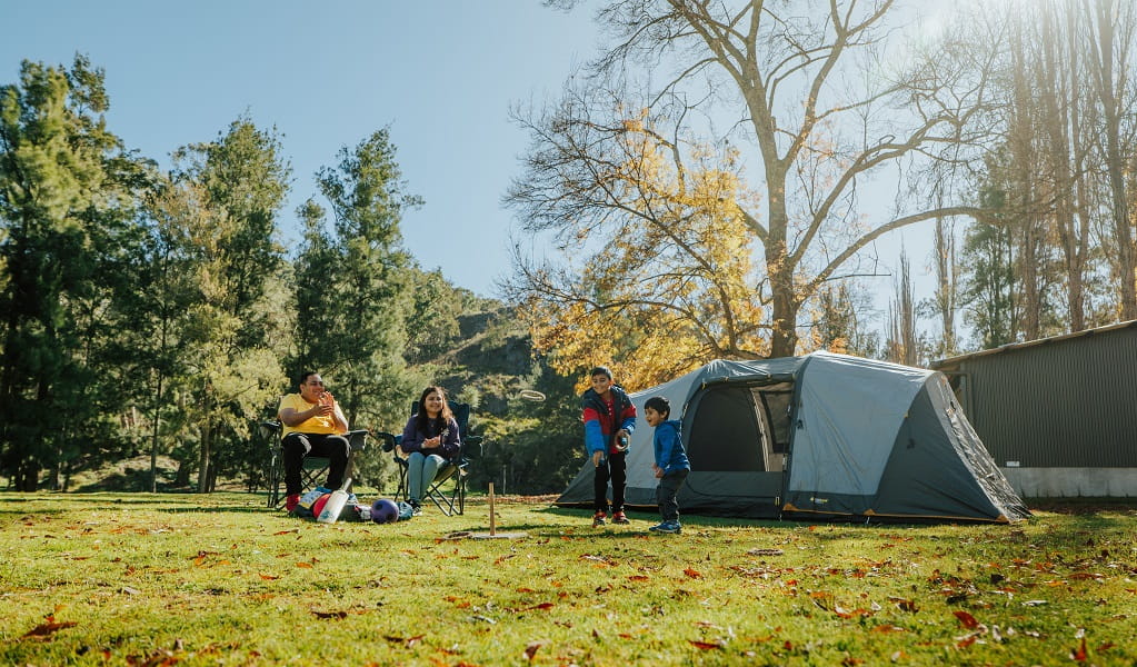 Kids play quoits beside their tent in Wombeyan Caves campground, as their parents look on. Credit: Remy Brand/DPE &copy; Remy Brand