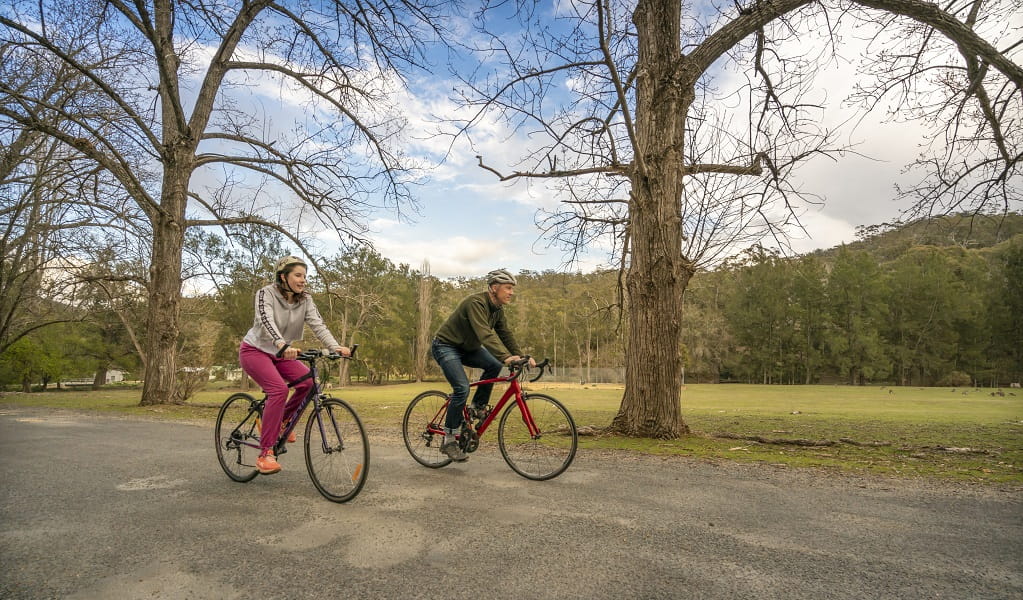 A man and a woman enjoy a bike ride near Wombeyan picnic area. Photo: John Spencer &copy; DCCEEW