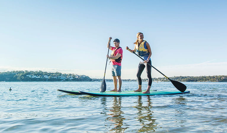 2 people stand up paddle boarding Bonnie Vale Royal National Park. Simone Cottrell/DPIE