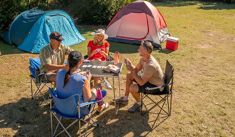 A group of friends playing cards next to their tents. Photo: John Spencer/DPIE