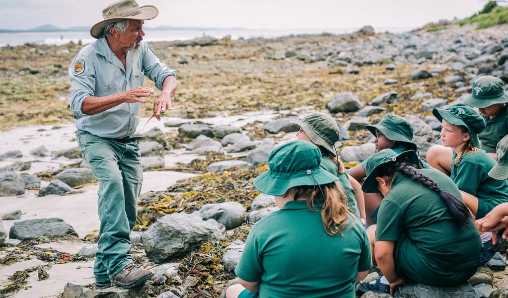 Uncle Mark Flanders, Aboriginal Discovery ranger, with school children learning about the Arrawarra fishtraps, North Coast. Photo: Jay Black &copy; DPE
