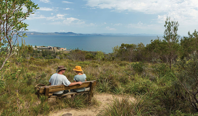 A couple rest on a picnic bench with an ocean view on Monument track. Credit: David Finnegan &copy; David Finnegan/DPIE