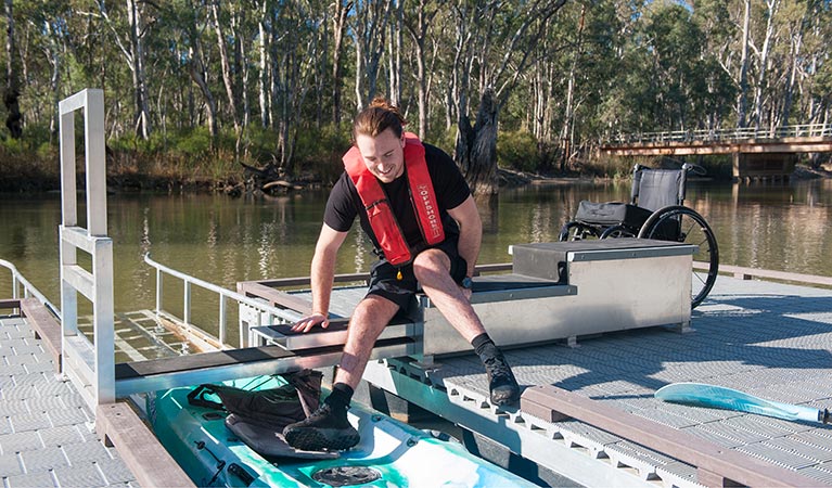 Man moving from stair platform into kayak at Edward River Bridge kayak launch. Photo: Rhys Leslie/OEH