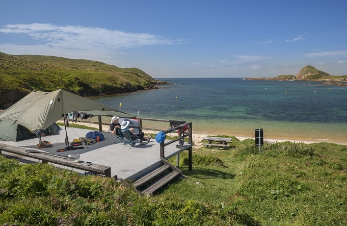 A couple enjoy secluded beach views from a camping platform at Broughton Island campground, Myall Lakes National Park. Photo: John Spencer/OEH