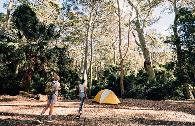 A couple walk to their tent at Depot Beach campground, Murramarang National Park. Photo credit: Melissa Findley &copy; OEH.